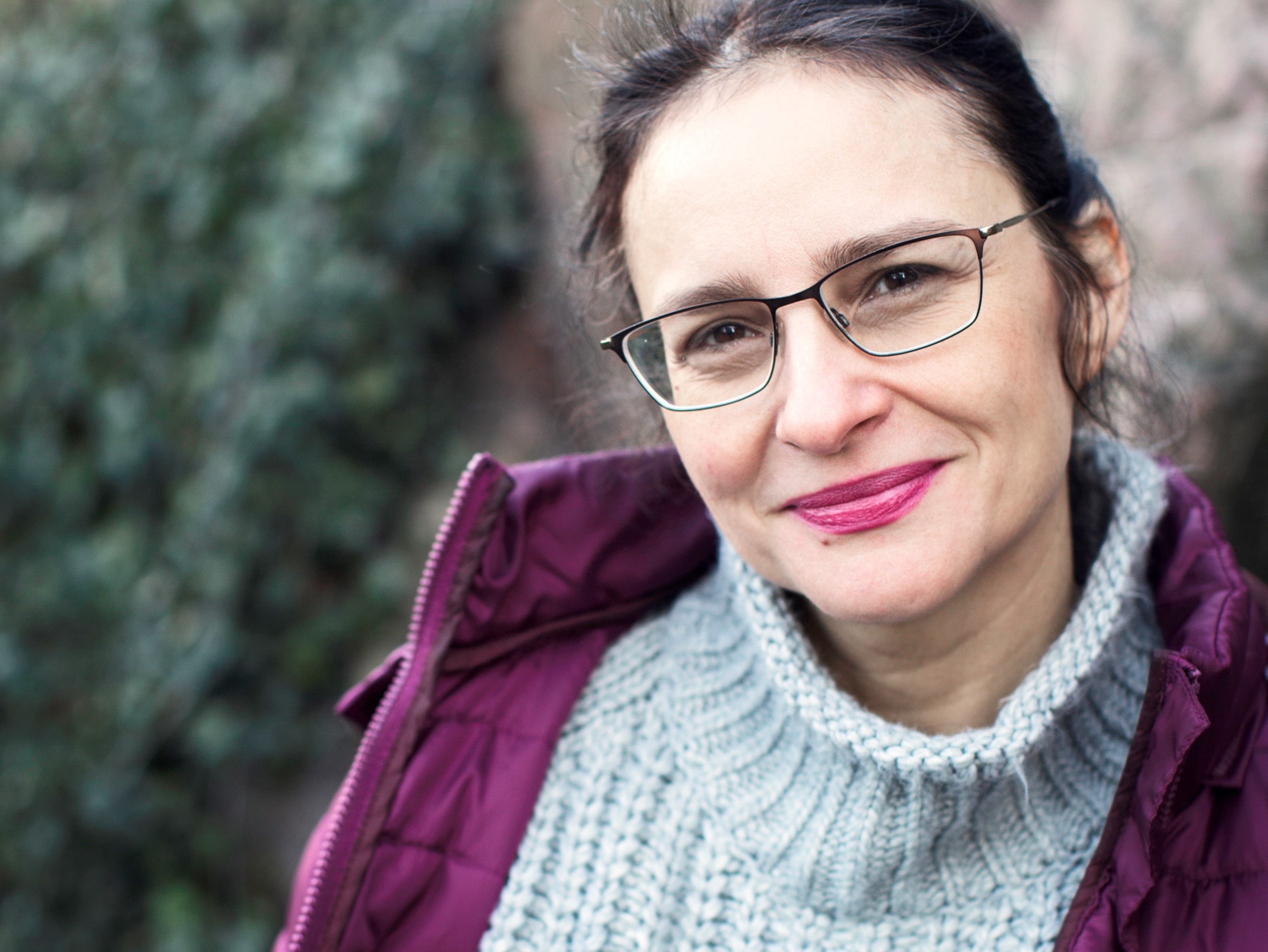 Porträtt av Nicoleta Eserblom, lutad mot en stenvägg. Foto: Rebecka Uhlin.