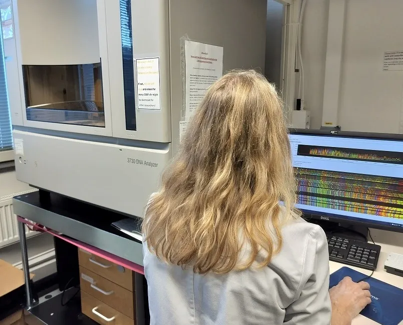Researchers with her back to the camera, sitting at the equipment.