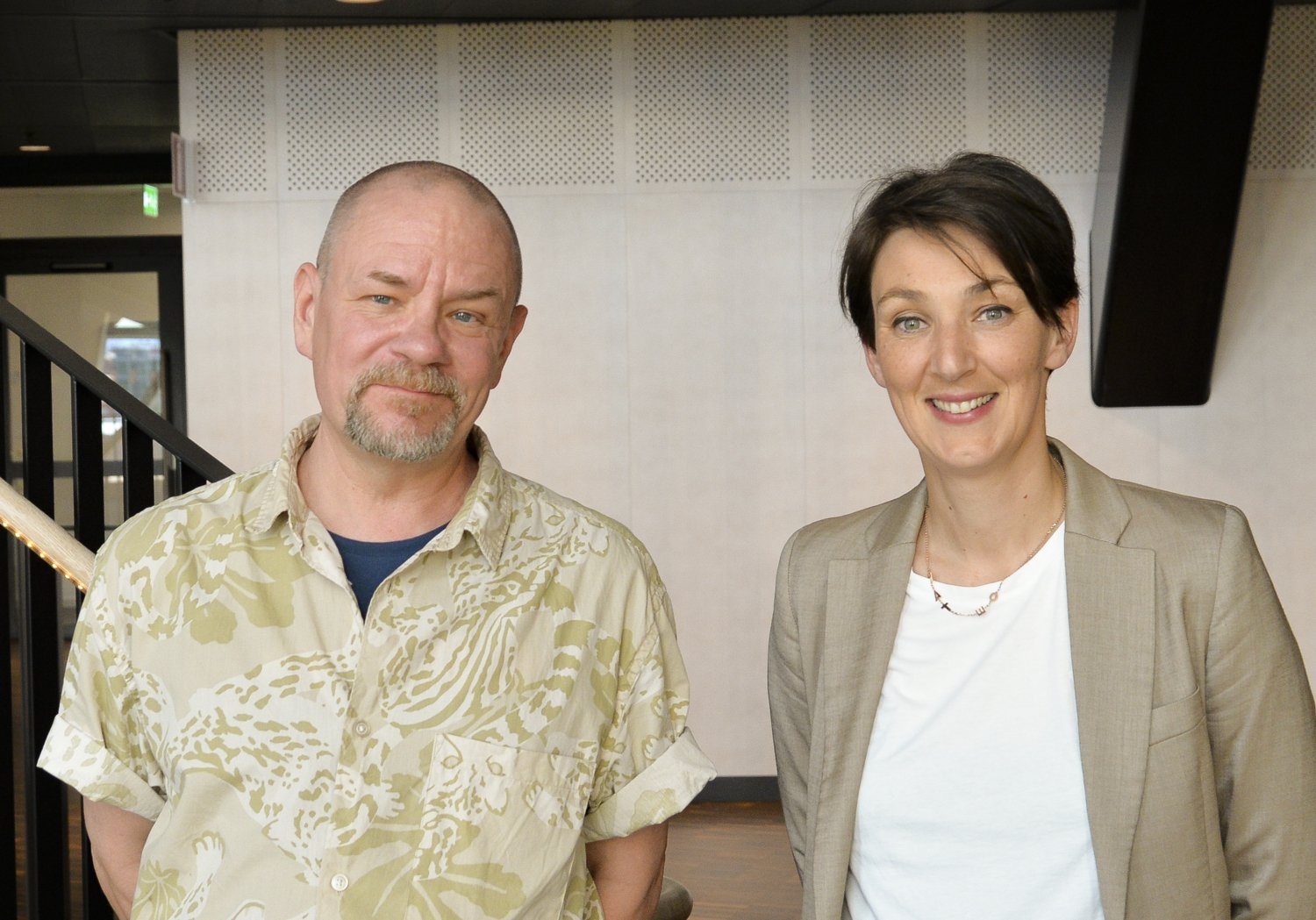 Porträtt av två personer framför trappa inomhus.