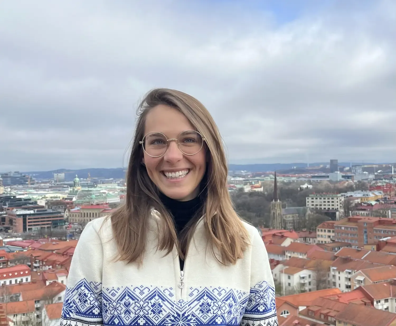 Portrait picture of a woman with long brown hair and round glasses.