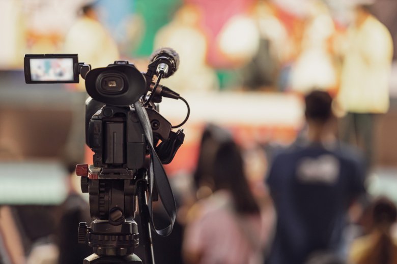 En filmkamera riktas mot människor i oskärpa.