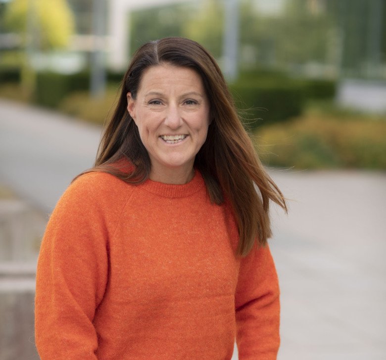 Porträtt av Erika Franzén utomhus. Hon har en orange tröja på sig och långt mellanblont hår.