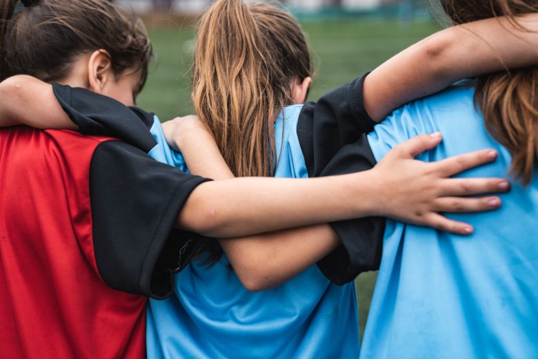 Three soccer girls hugging each other