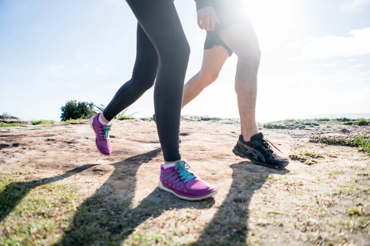 Personer i gympaskor som promenerar. Delvis motljus.
