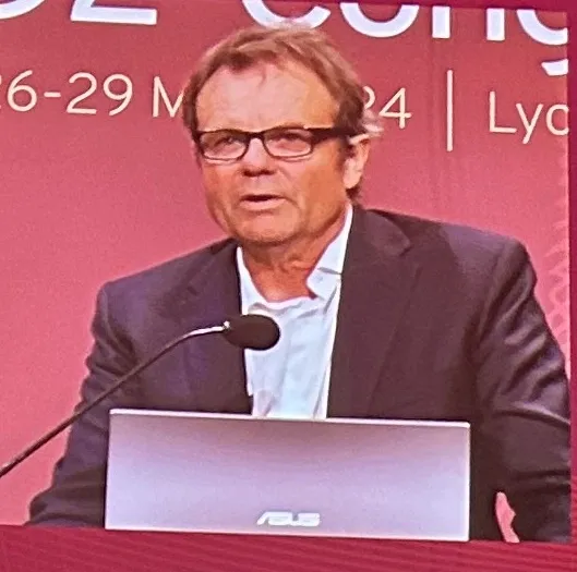 A man is standing at a podium and speaking into a microphone.