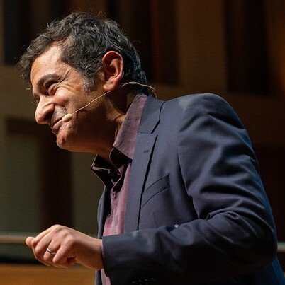 En man som bär en mikrofon och en mörk kostym.