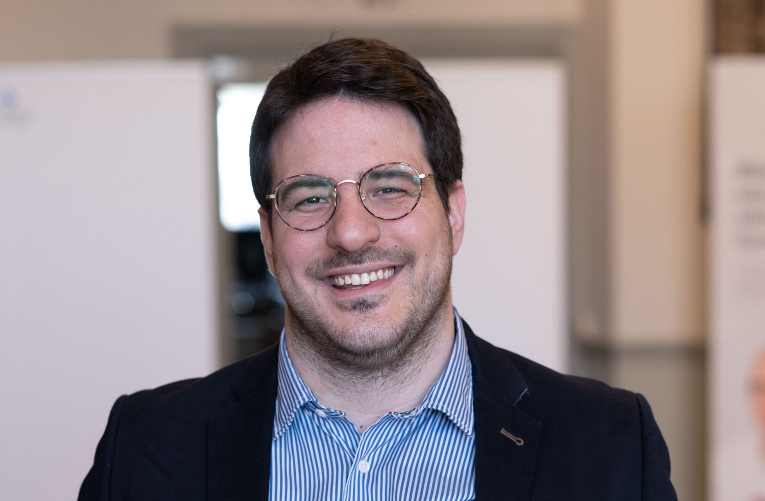 Ioannis Zerdes dressed in black jacket and a striped shirt.