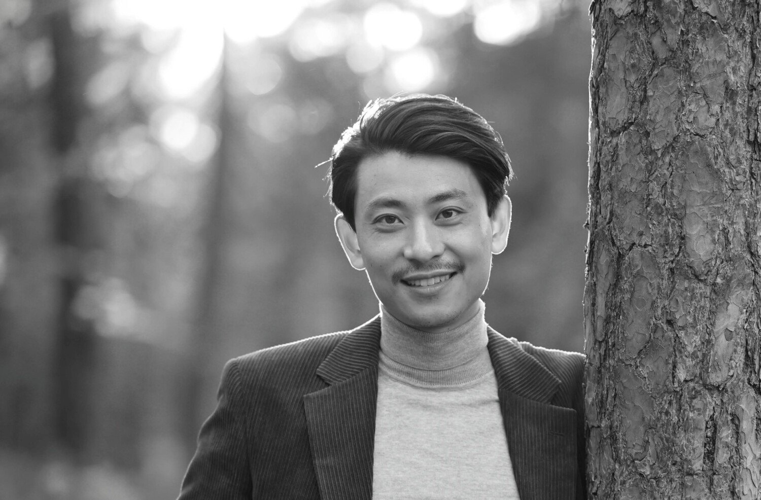 Svartvitt fotografi av leende man i kavaj.