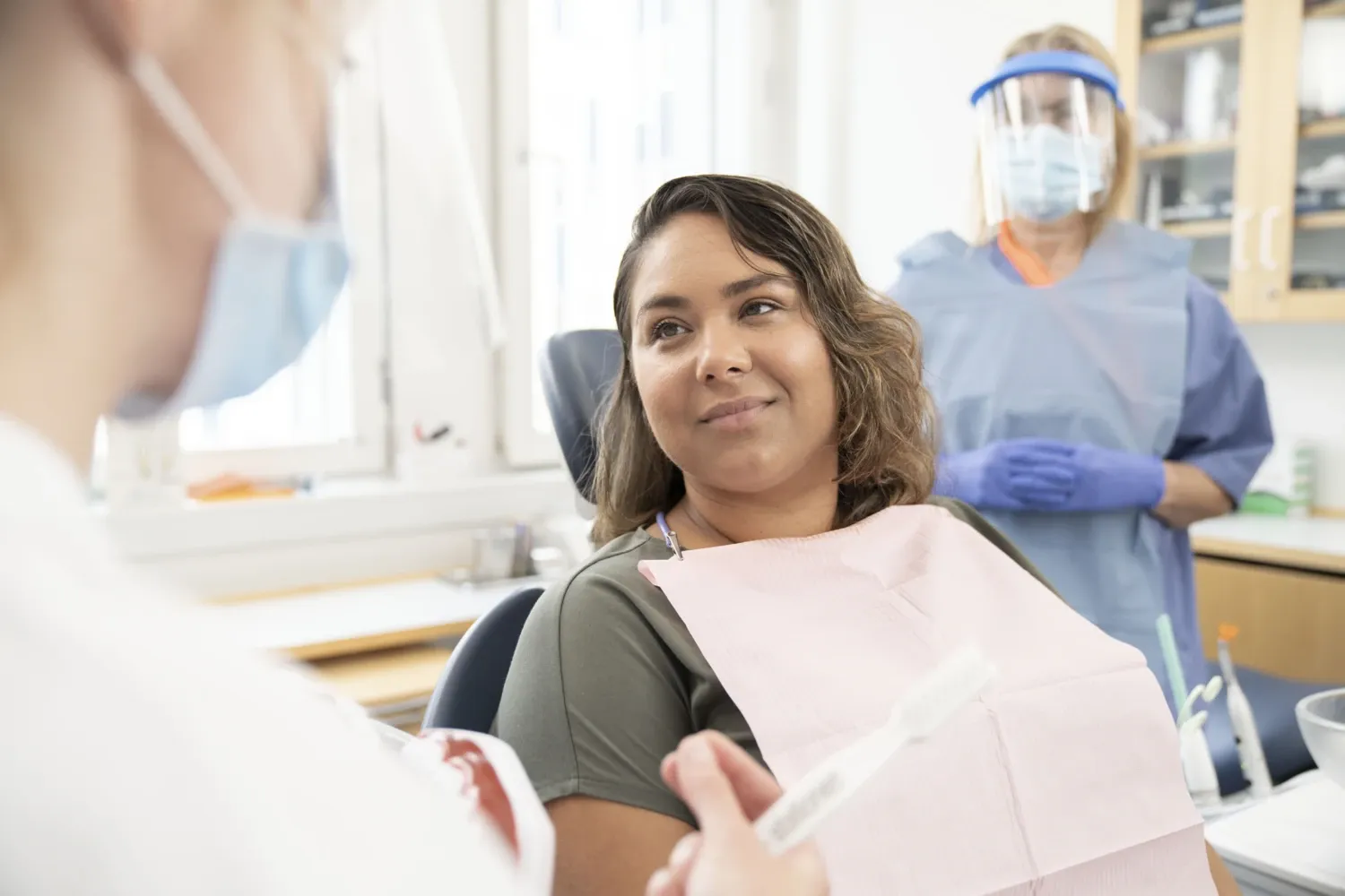 Dental treatment, patient in the chair with dentist and detnal nurse.