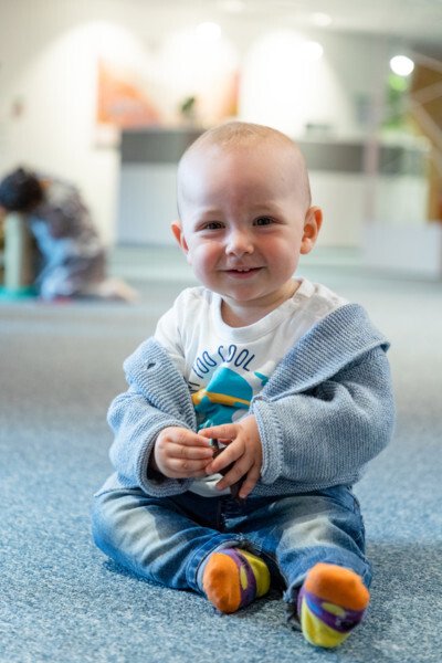 Baby sitter på golvet och ser glad ut