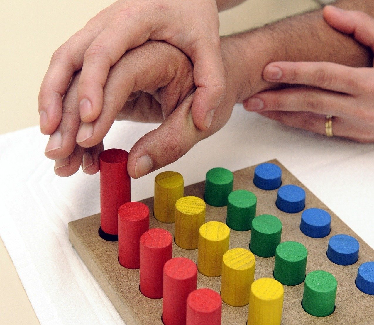En hand som håller en annans hand som plockar med träpinnar på en platta.