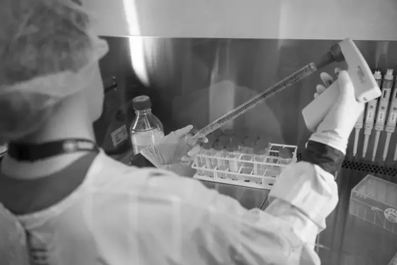 Researcher pipetting a yellow liquid in a LAF hood