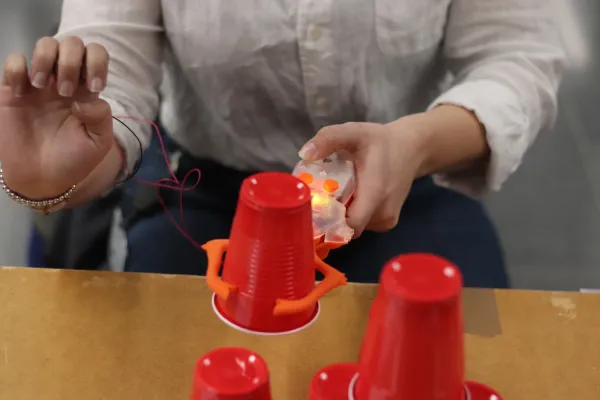 Hands of guest holding and trying to control a robot claw performing various tasks.