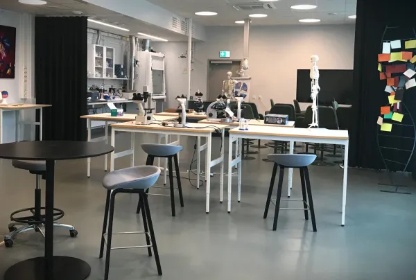 Bord och stolar. Det står mikroskop på en del av borden. Längst bort syns en modell av ett skelett.