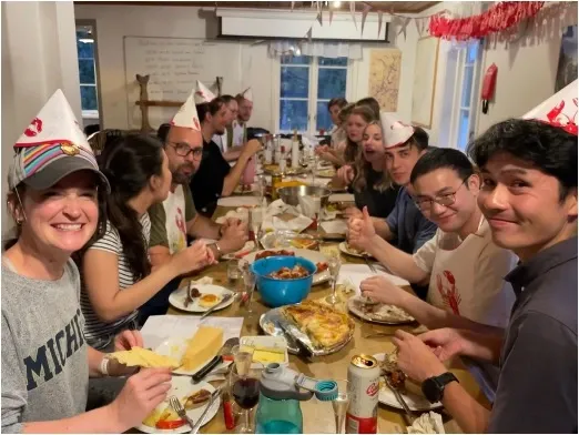 A group smiling and enjoying dinner together in their crayfish hats.