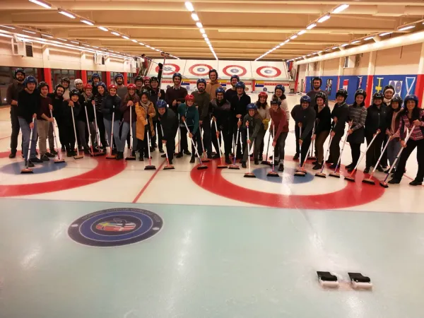 Group picture on the ice with helmets and brushes.