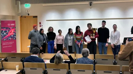 8 people flanking the winner Daniel Andersson holding the trophy and diploma