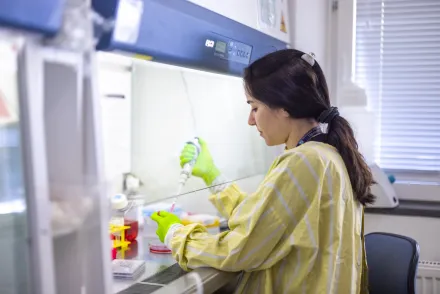 Woman in lab environment working with a pipette.